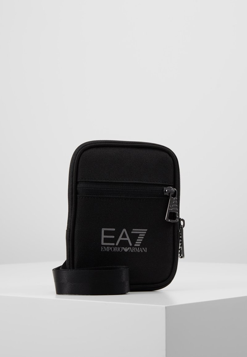 Borsa a tracolla nera in nylon con chiusura a zip, caratterizzata dal logo EA7 argentato, una superficie testurizzata e una tracolla regolabile.