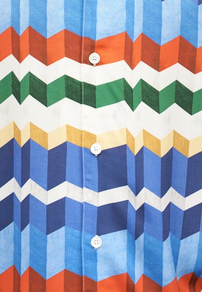 Χρωματιστό ύφασμα πουκάμισου με γεωμετρικές ζιγκ ζαγκ λωρίδες σε μπλε, λευκό, κίτρινο, πράσινο, πορτοκαλί και καφέ, με λευκά κουμπιά στη μέση.