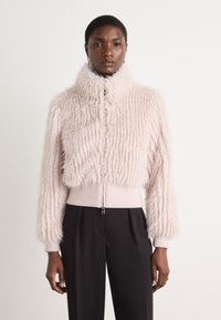 Faux fur cropped jack in lichtroze met ribgebreide manchet en onderrand, voorzien van een hoge kraag en zichtbare rits. Zachte textuur, geweven ontwerp.