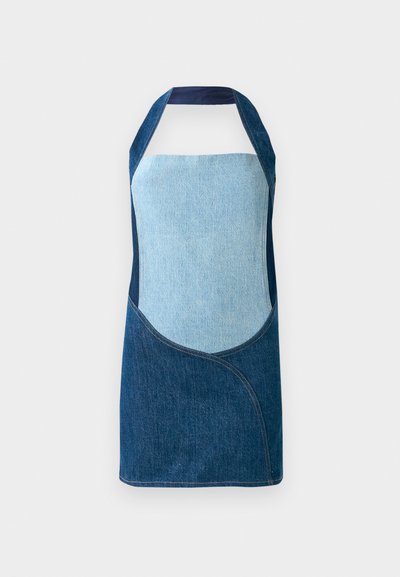 Denim delovni predpasnik, ki združuje svetle in temne modre tkanine, s krožnimi panelnimi oblikami in silhueto na vratu.