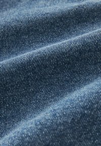 Denimstof in een middelblauwe kleur, met een gestructureerde weving en een lichte glans. Het oppervlak vertoont subtiele variaties in tint en patroon.