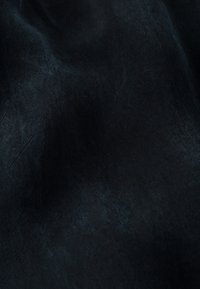 Černá texturovaná tkanina s jemným leskem, s hladkým povrchem a mírným vlnitým vzorem, naznačující lehký a splývavý materiál.