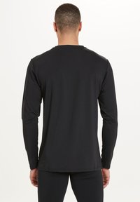 Svart långärmad skjorta i mjukt tyg, med en klassisk rund hals och en skräddarsydd passform. Inga synliga mönster eller logotyper.