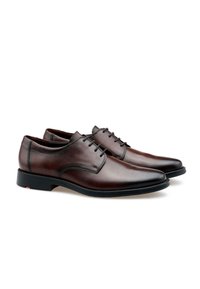 Zapatos de vestir de cuero marrón con acabado pulido, cordones finos y un diseño de punta redonda. Presenta una suela negra sutil con un acento rojo.