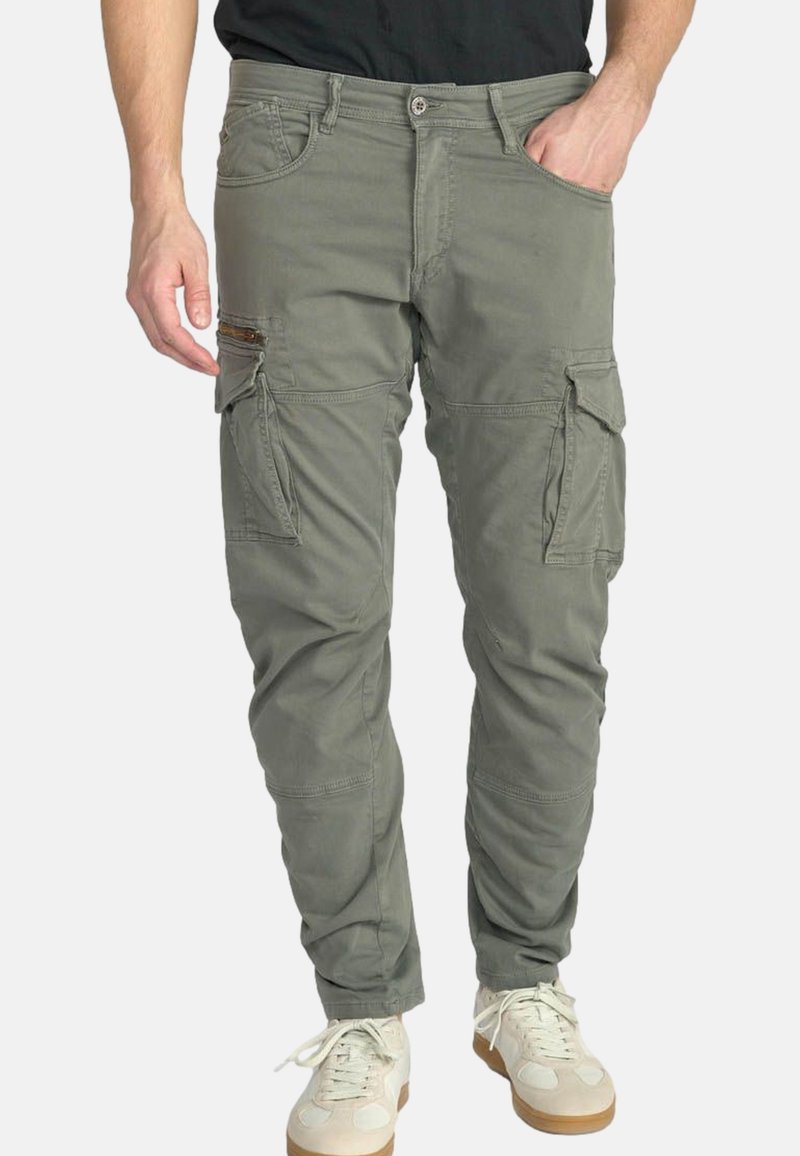 Cargo-broeken in olijfgroene stof met meerdere zakken, een ritszak aan de zijkant en elastische boorden bij de enkels. Gelaagd, duurzaam materiaal.
