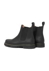 Bottines Chelsea en cuir noir avec panneaux latéraux élastiques, finition texturée et semelles en caoutchouc robustes. Des surpiqûres dorées mettent en valeur la semelle.
