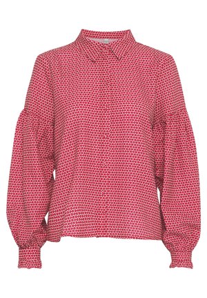 Blouse rouge avec un col, présentant un motif ovale blanc répété, des manches bouffantes longues et des boutons sur le devant. Texture de tissu douce.