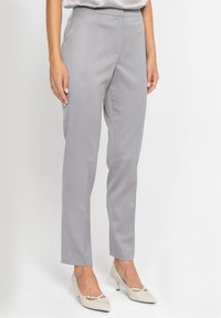 Szare dopasowane spodnie o wąskim kroju, z gładkim przodem i gładką teksturą, zestawione z jasnymi obcasami dla eleganckiego wyglądu.