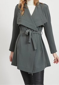 Cappotto grigio avvolgente con un design doppiopetto, ampi revers, cintura in vita e tasche frontali. Tessuto liscio con vestibilità su misura.