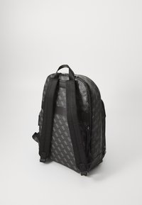 Zaino nero con un esterno a motivi e un logo discreto, realizzato in nylon, dotato di due spallacci regolabili e una maniglia superiore per il trasporto.