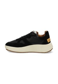 Basket noire avec un dessus en daim et en cuir, semelle intermédiaire blanche épaisse avec une texture striée, et un accent en cuir marron au niveau du talon.