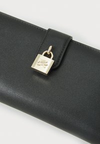 Portefeuille en faux cuir noir avec une finition texturée, mettant en avant un accent de cadenas doré. Le portefeuille dispose d'une fermeture à rabat et d'un design élégant.