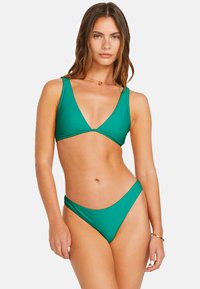 Twee-delige bikini set in effen groen, met een driehoekige top en een low-rise onderkant met minimale bedekking en een gladde textuur.