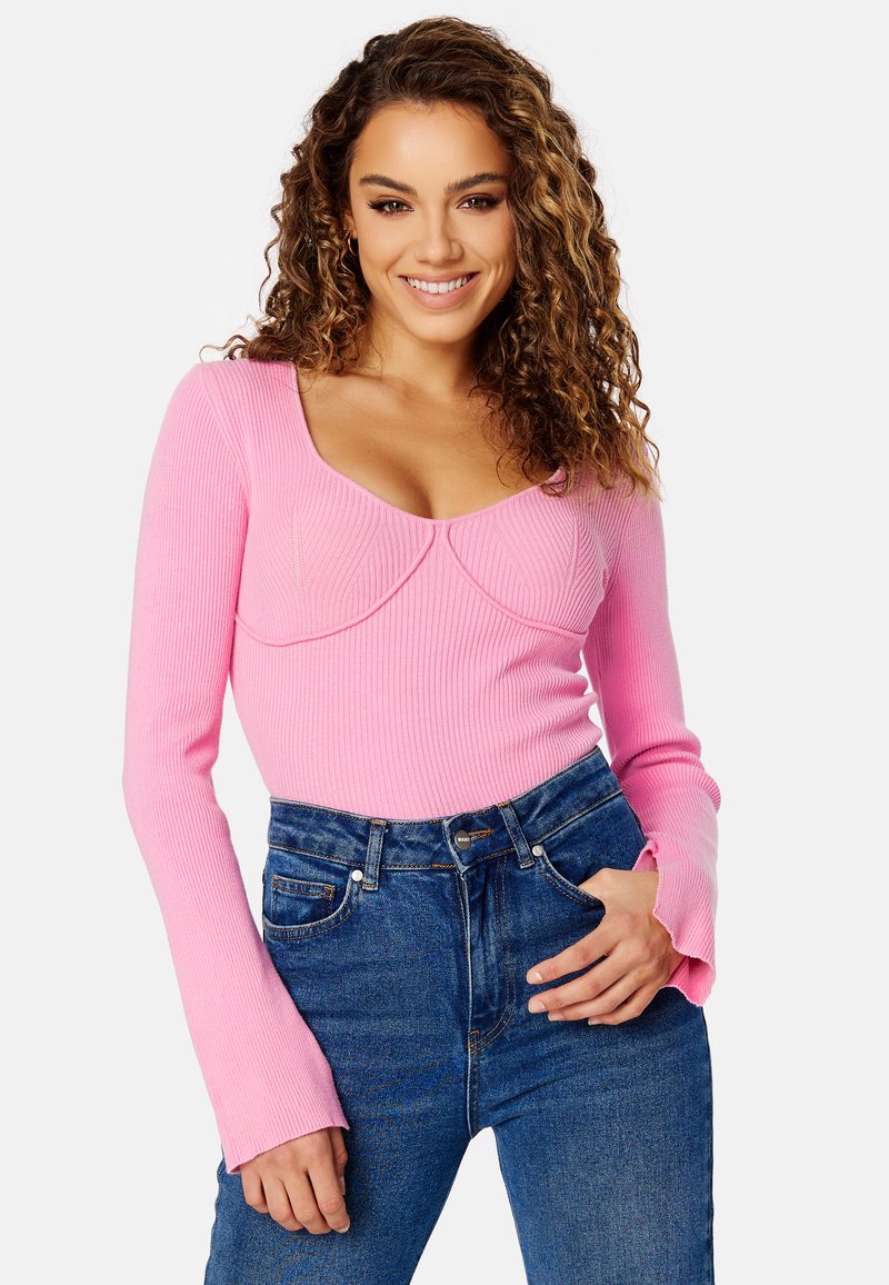 Maglietta lunga a righe rosa con scollo a barchetta e dettagli cuciti. Abbinata a jeans in denim blu a vita alta.