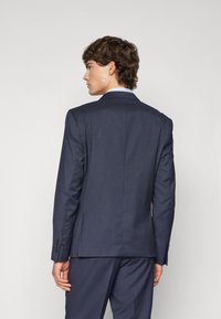 Námornícka sako s textúrovanou tkaninou, slim fit, so šitými klopami a manžetami na tri gombíky, prezentujúce čísty a moderný dizajn.