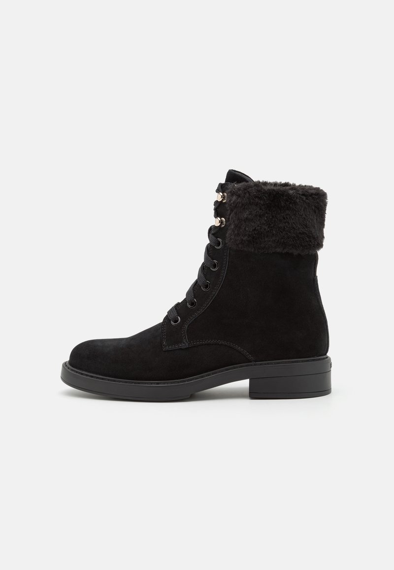 Stivale alla caviglia in suede nero con collo in pelliccia sintetica, lacci sul davanti, occhielli metallici e tacco a blocco. Texture liscia e design robusto.
