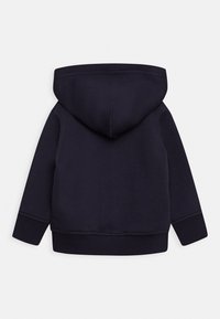Sudadera con capucha de color azul marino con una textura suave, puños y dobladillo acanalados; presenta una única costura curva en la parte trasera de la capucha.