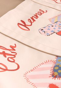 Drobės krepšys, šviesiai kūno spalvos, su raudonais užrašais. Papuoštas šuns iliustracija ir įvairiaspalviais raštais, įskaitant žvaigždes ir taškelius.