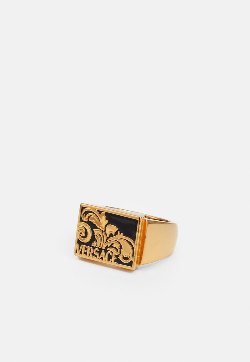 Bague rectangulaire en métal doré avec dessus en émail noir ornée d'un motif floral doré orné et inscription "VERSACE".