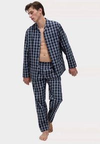 Ensemble de pyjama à carreaux bleu marine et blanc en tissu léger, comprenant une chemise à boutons et un pantalon à taille élastique, coupe décontractée.