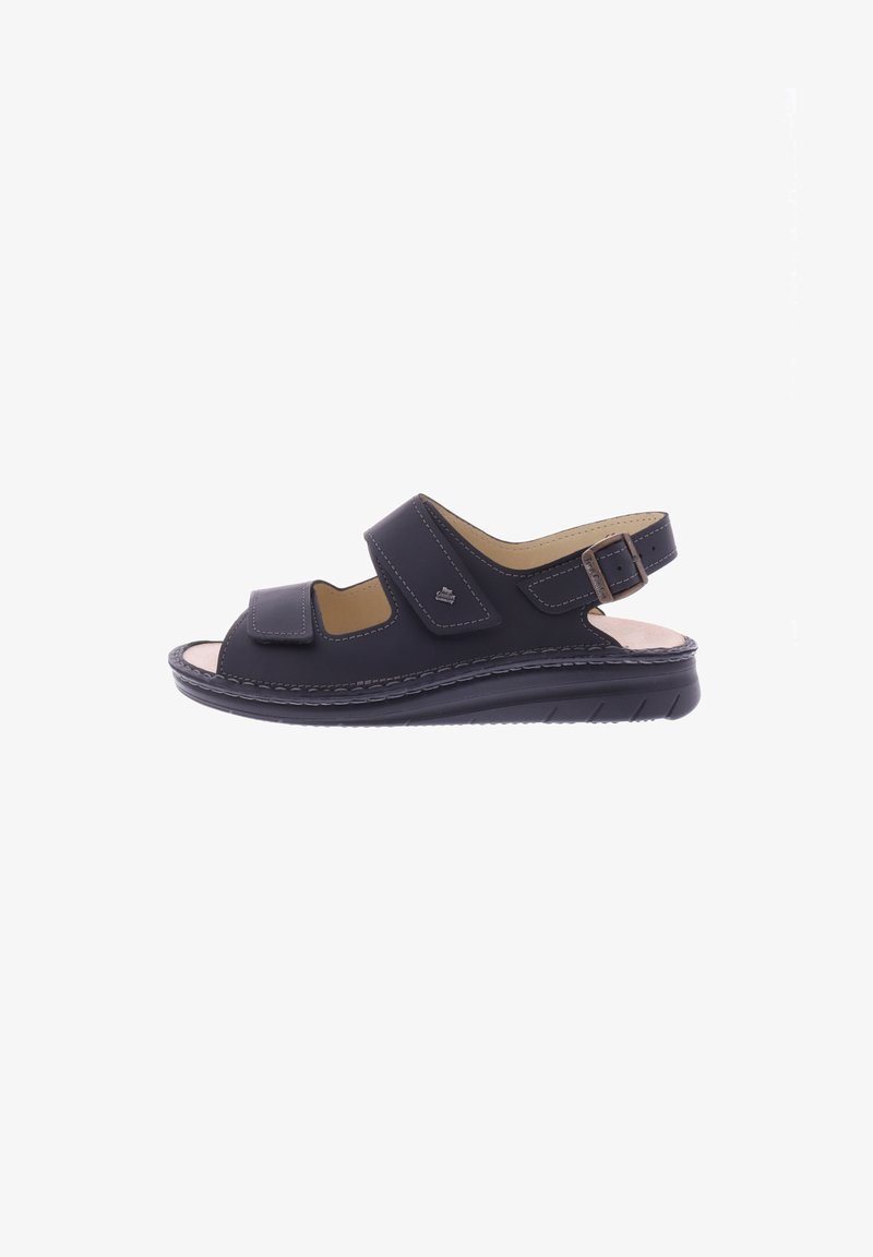 Black leather sandal with two adjustable Velcro straps, open toe, and a textured sole. Features a low heel and stitched accents.