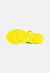 Suola di sneaker gialla brillante con un design testurizzato e a motivi per una migliore aderenza. Presenta una forma piatta e un'area della punta curvata.
