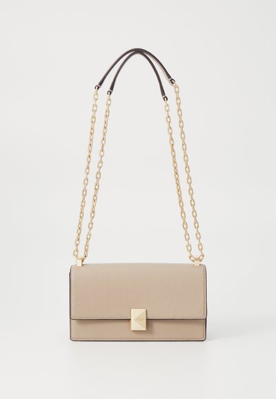 Beige leather handbag with gold chain straps, rectangular shape, textured surface, and a prominent square clasp detail on the front.