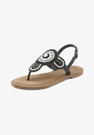 Black beaded thong sandal with a circular embellishment, featuring a cushioned tan footbed and adjustable strap. Textured surface detailing.