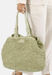 Lichtgroene geweven totebag met gladde handvatten, een gestructureerde vorm en een subtiel label. Heeft een textuur oppervlak en een ruime binnenkant.