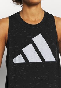 Canotta atletica nera senza maniche con un grande logo Adidas bianco in un design triangolare. La texture del tessuto presenta un sottile dettaglio mélange.