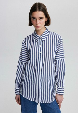 Striped button-up shirt featuring alternating navy and white vertical stripes, a pointed collar, and long sleeves with a rounded hem.