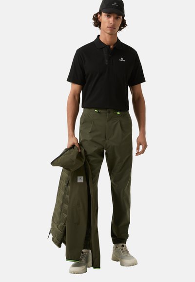 Black polo shirt, olive green pants, and matching jacket. Pants feature bright green accents; light-colored footwear completes the outfit.
