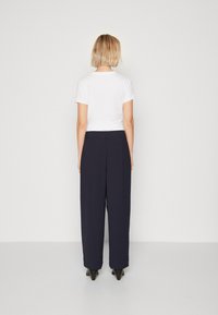 Valkoinen lyhythihainen paita yhdistettynä korkeavyötäröisiin, merimiessinisiin leveälahkeisiin housuihin. Asu on viimeistelty mustilla korkokengillä.