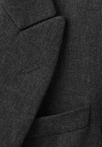 Detaliile unui sacou din lână de culoare gri închis, evidențiind un material texturat, rever ascuțit și o buzunar cusut cu grijă. Pune accent pe un design elegant și o structură bine definită.