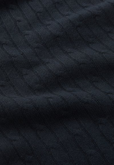 Black knitted fabric featuring a raised cable pattern, textured with soft, thick yarn, creating waves and ridges across the surface.