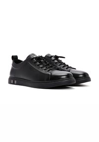 Sneaker in pelle nera con punta arrotondata, design elegante, lacci in tessuto e suola testurizzata con due accenti argentati.