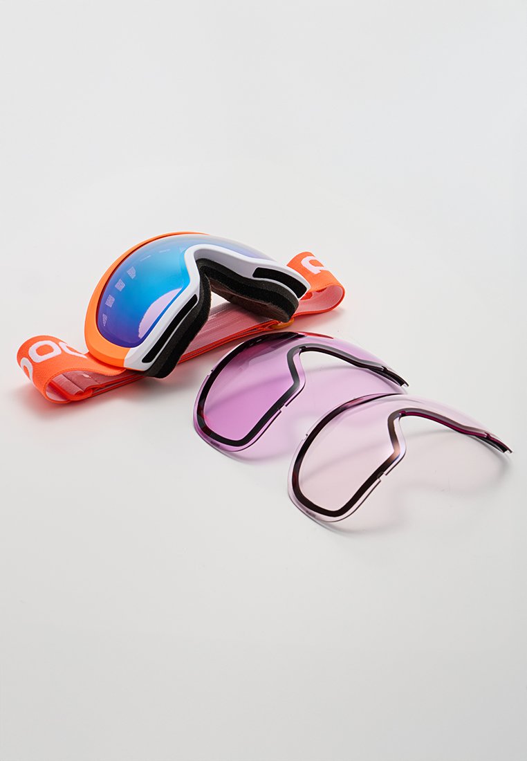 Pomarańczowe gogle narciarskie z refleksyjną niebieską soczewką oraz dwiema wymiennymi soczewkami w fioletowym odcieniu na białym tle.