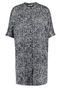 Valkoinen ja musta lyhythihainen nappipaitaa abstraktilla täpläkuviolla ja pyöreällä kaula-aukolla.