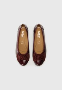 Ballet flats en cuir bordeaux avec une finition texturée, dotées d'un détail en daim au centre sous forme de nœud, d'une semelle intérieure rembourrée et d'un design à bout rond.
