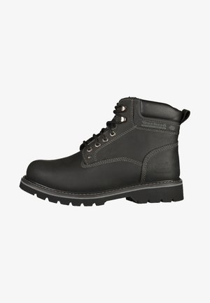 Botte de travail en cuir noir au design robuste, avec un embout renforcé, des œillets en métal et une semelle épaisse et robuste. Détails de surpiqûres contrastés.