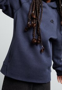 Mörkblå Nike sweatshirt med huva, med en liten svart logo, ribbad mudd och en avslappnad passform. Mjuk textur med sömlös detaljering.