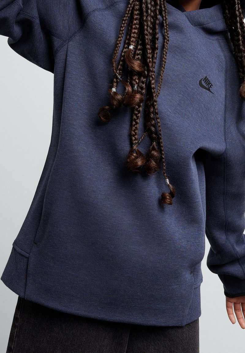 Mörkblå Nike sweatshirt med huva, med en liten svart logo, ribbad mudd och en avslappnad passform. Mjuk textur med sömlös detaljering.