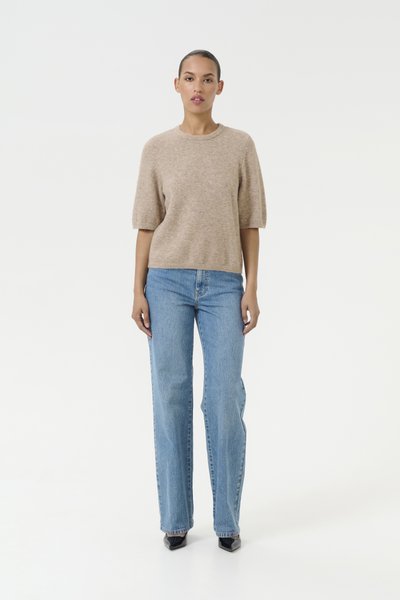 Pull beige à manches courtes avec un col rond, associé à un jean droit bleu clair. La tenue a une texture douce et une coupe décontractée.