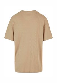 T-shirt en maille côtelée beige à manches courtes avec un col rond, vu de dos sur fond blanc.