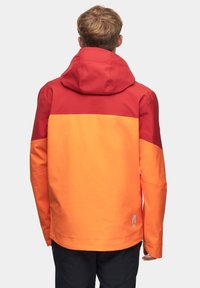 Kurtka z kapturem z kolorowym blokiem w odcieniach czerwieni, pomarańczy i żółci. Wykonana z teksturowanego materiału o gładkim wykończeniu.