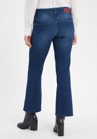 Donkerblauwe uitlopende spijkerbroek met een ruwe zoom, voorzien van twee achterzakken en een leren merklabel op de tailleband. Gelaagde denim stof.