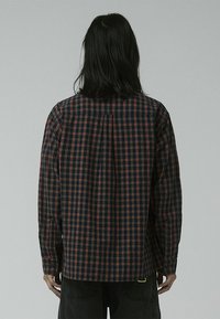 Checked shirt in navy, red, and white. Button-down design with long sleeves, rear yoke, and a curved hem. Soft fabric with a relaxed fit.