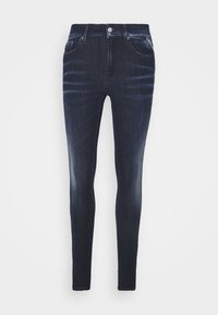 Jeans skinny de denim azul oscuro con una textura suave, con cinco bolsillos y cierre de botón en la parte delantera. Detalles descoloridos a lo largo de las piernas.