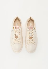 Beige lærersneakers med en glat overflade, der har pink metalliske accenter, gulddetaljer og en hjerteformet udsmykning på snørebåndene.