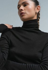 Czarny sweter golfowy z miękkiego materiału, z długimi rękawami i dopasowanym krojem. Gładka tekstura z minimalnymi detalami.